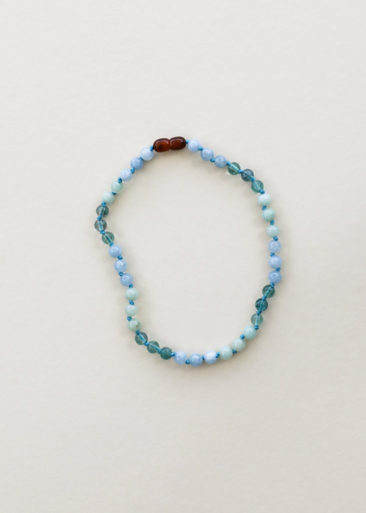 Gemstone bead necklace with light blue round beads and dark brown accent beads