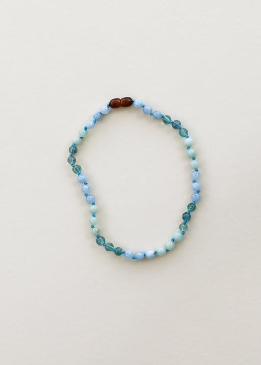 Gemstone bead necklace with light blue round beads and dark brown accent beads