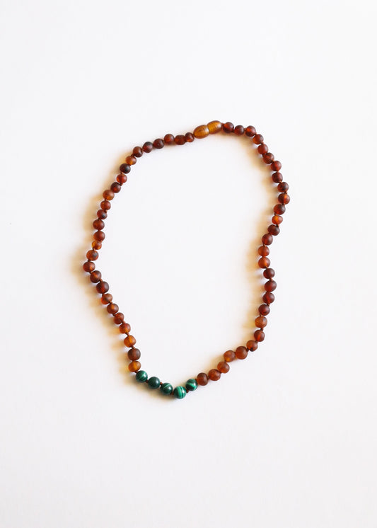 Amber bead necklace with green malachite bead at bottom center