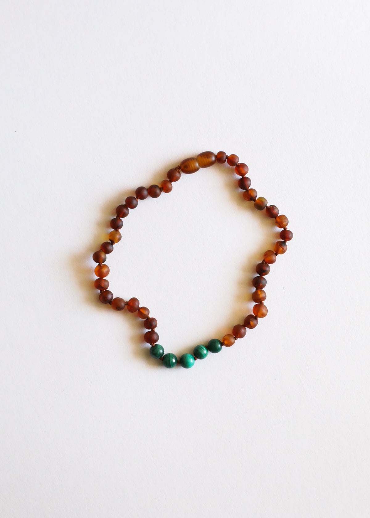 Raw amber bead necklace with small green malachite accents along lower edge