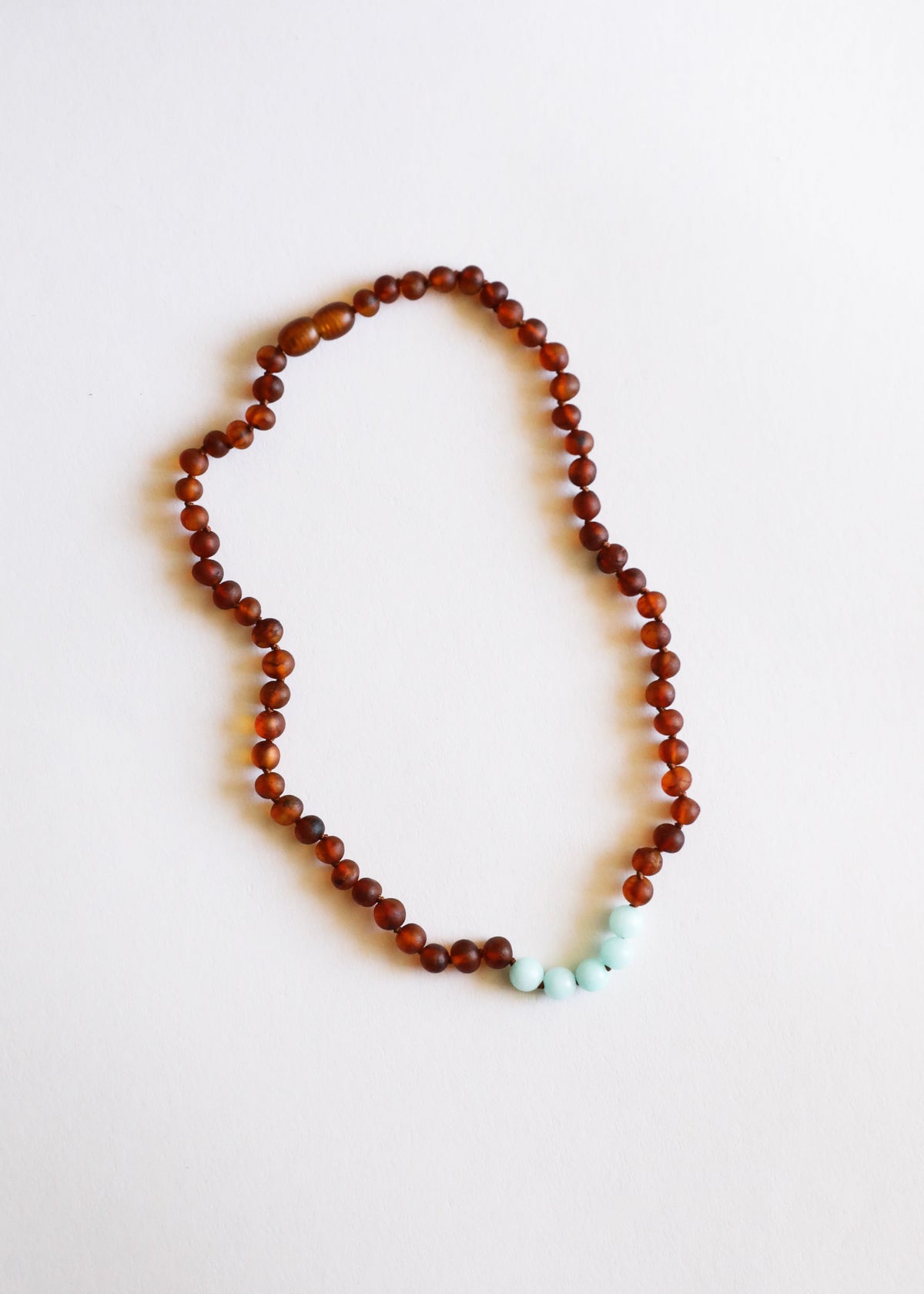 Cognac amber bead necklace with turquoise amazonite stones at lower edge for a curved drape