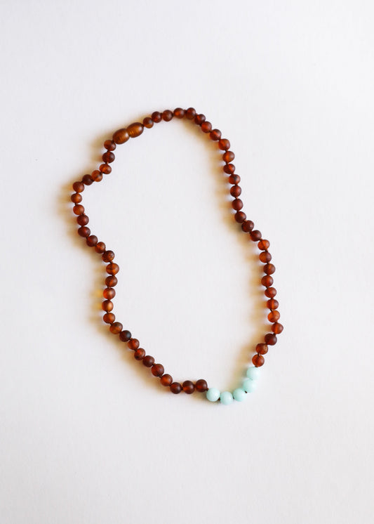 Cognac amber bead necklace with turquoise amazonite stones at lower edge for a curved drape