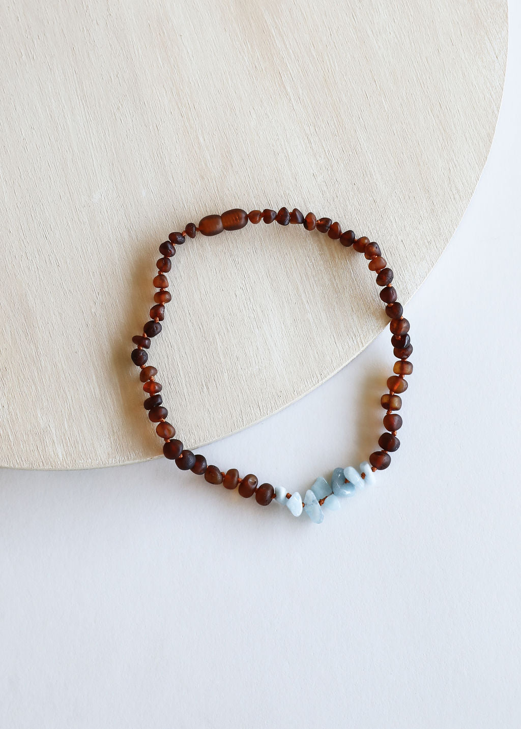 Amber-brown bead necklace with light blue stone accents on knotted cord