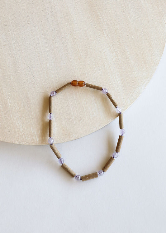 Beaded necklace with light brown wood-like beads, lavender cubes, and amber center bead