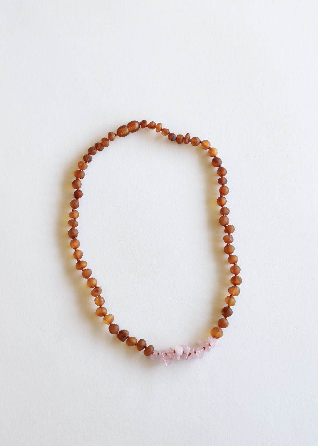 Raw amber beaded necklace with small pink stone detail at the lower center
