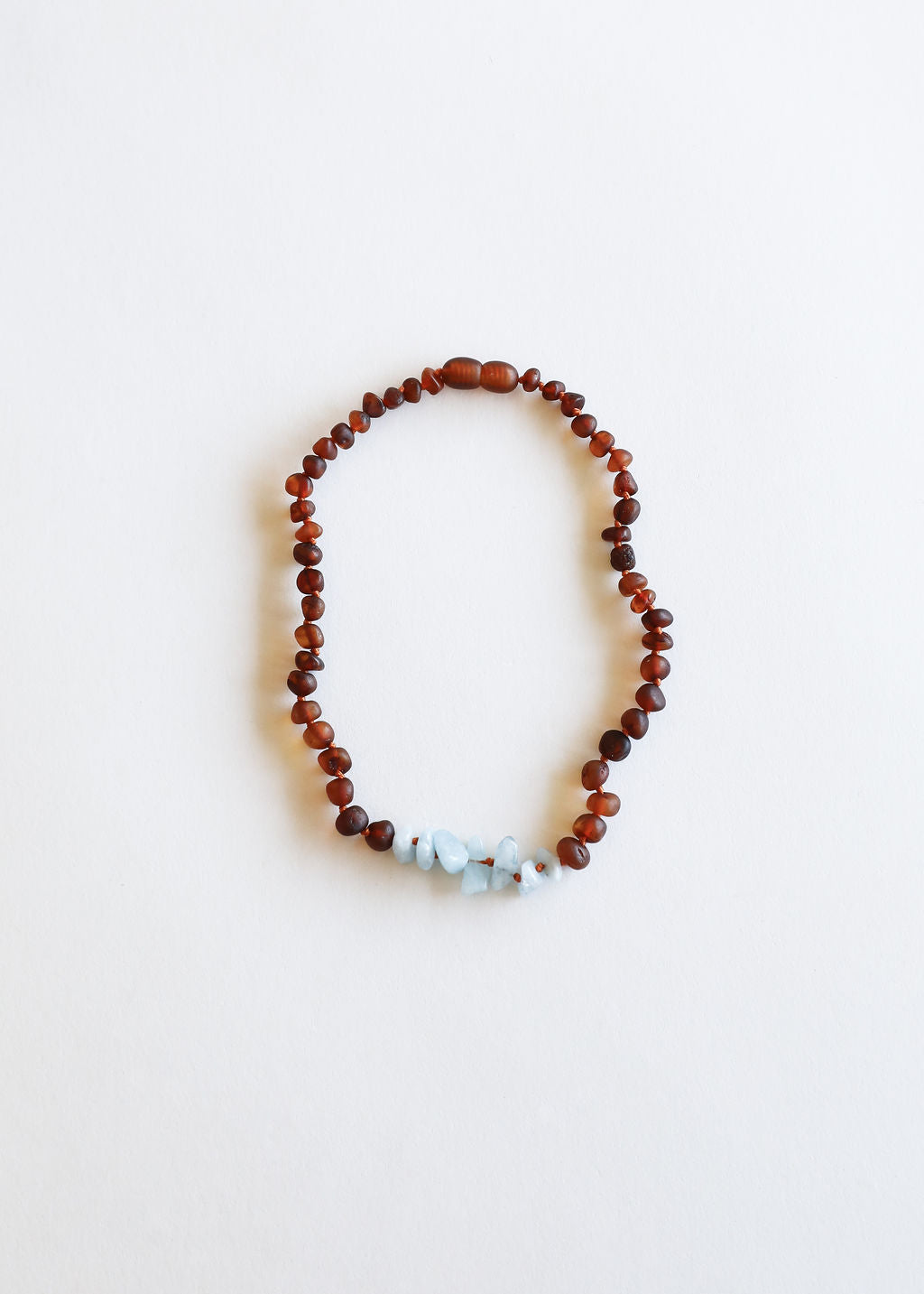 Amber-brown bead necklace with three light blue stone accents, looped shape