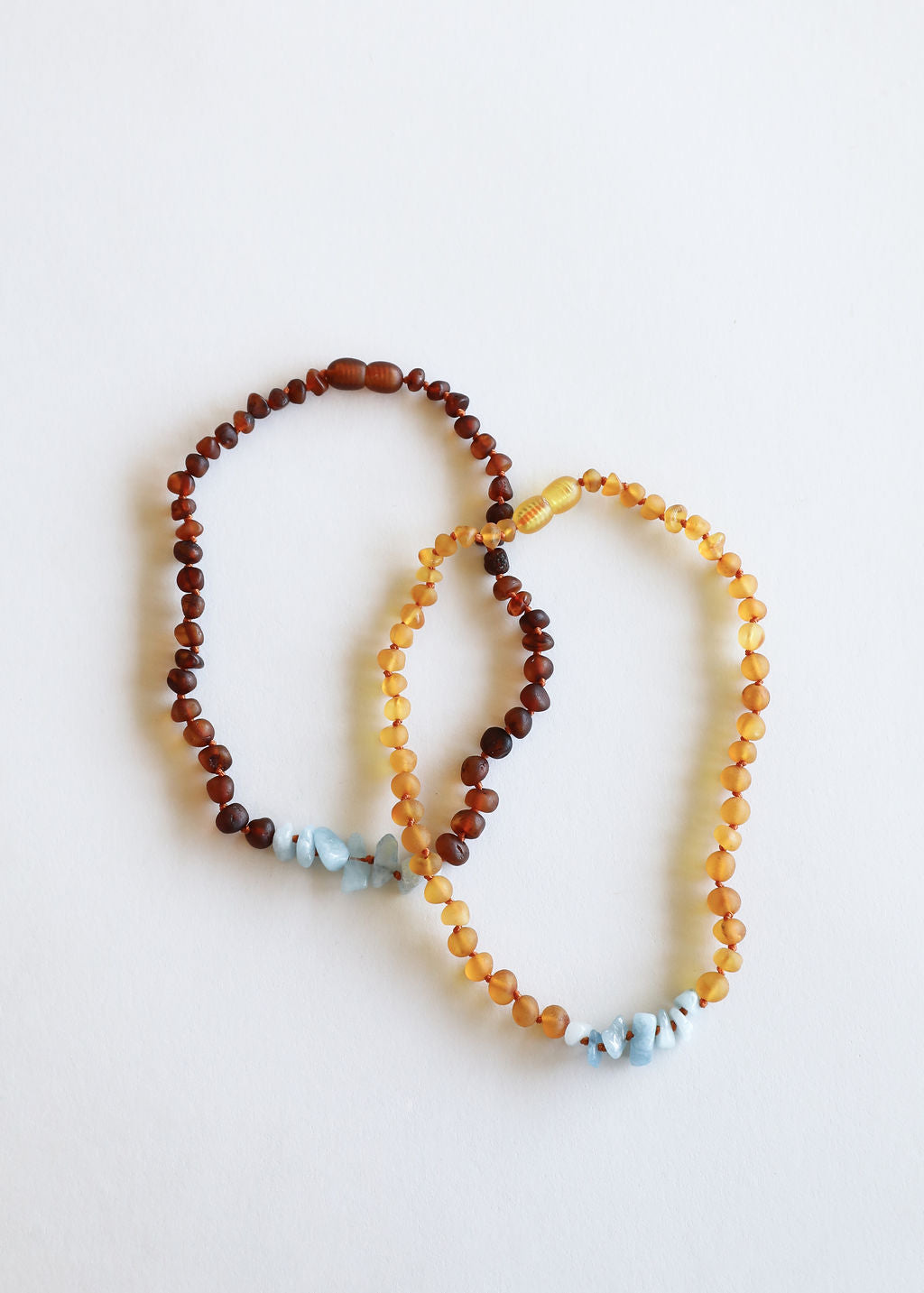 Layered beaded necklaces: amber-brown and golden with light blue stone accents