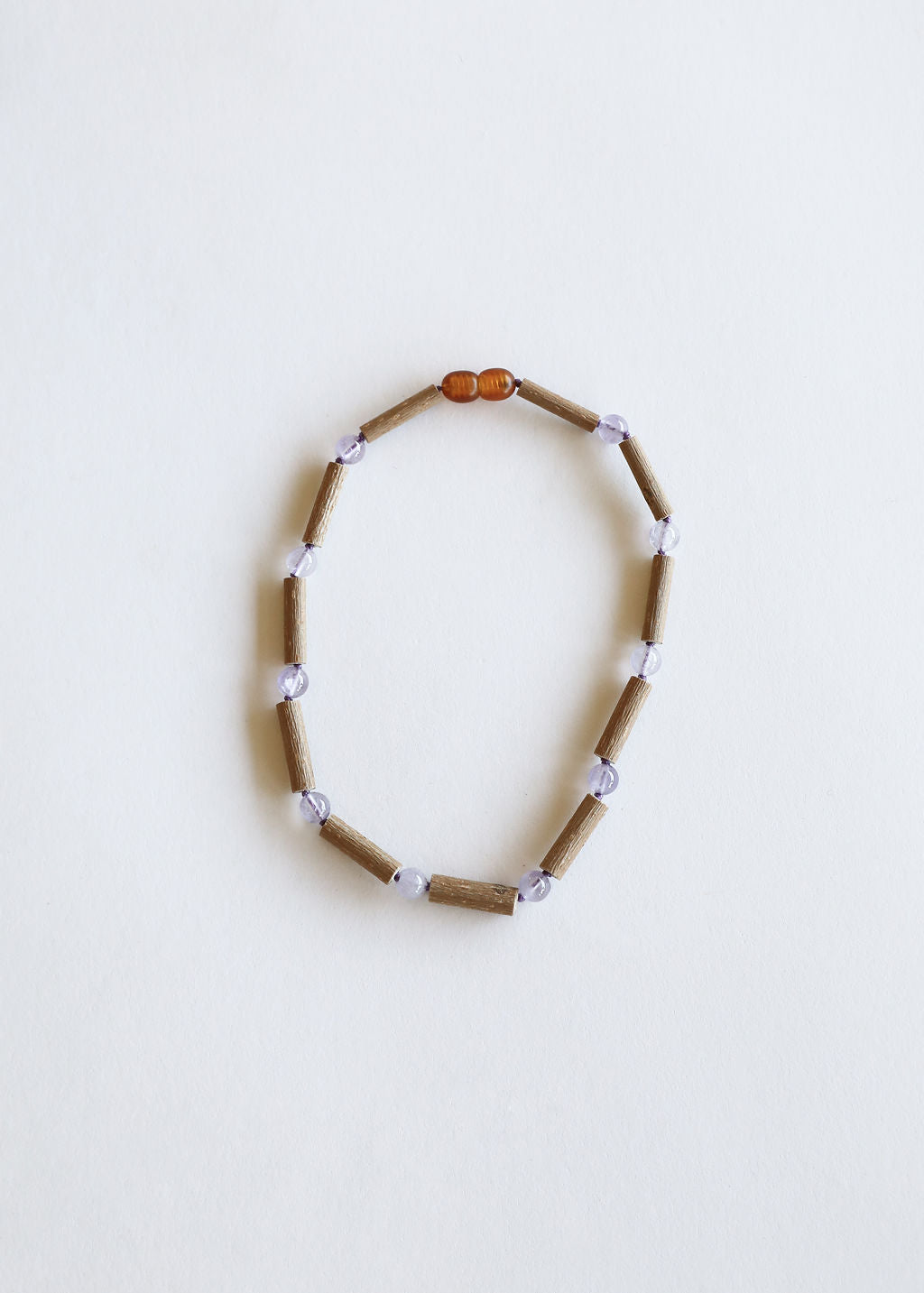 Beaded necklace strand with light brown and lavender beads, amber top center bead