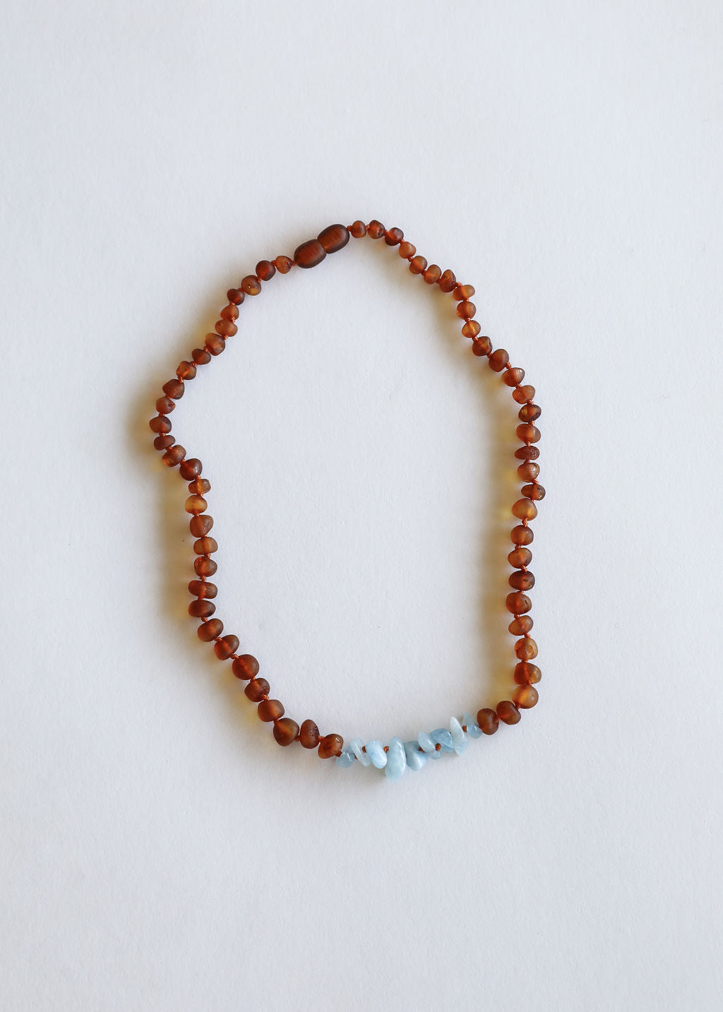 Amber-brown bead necklace with light blue stone accents, circular loop