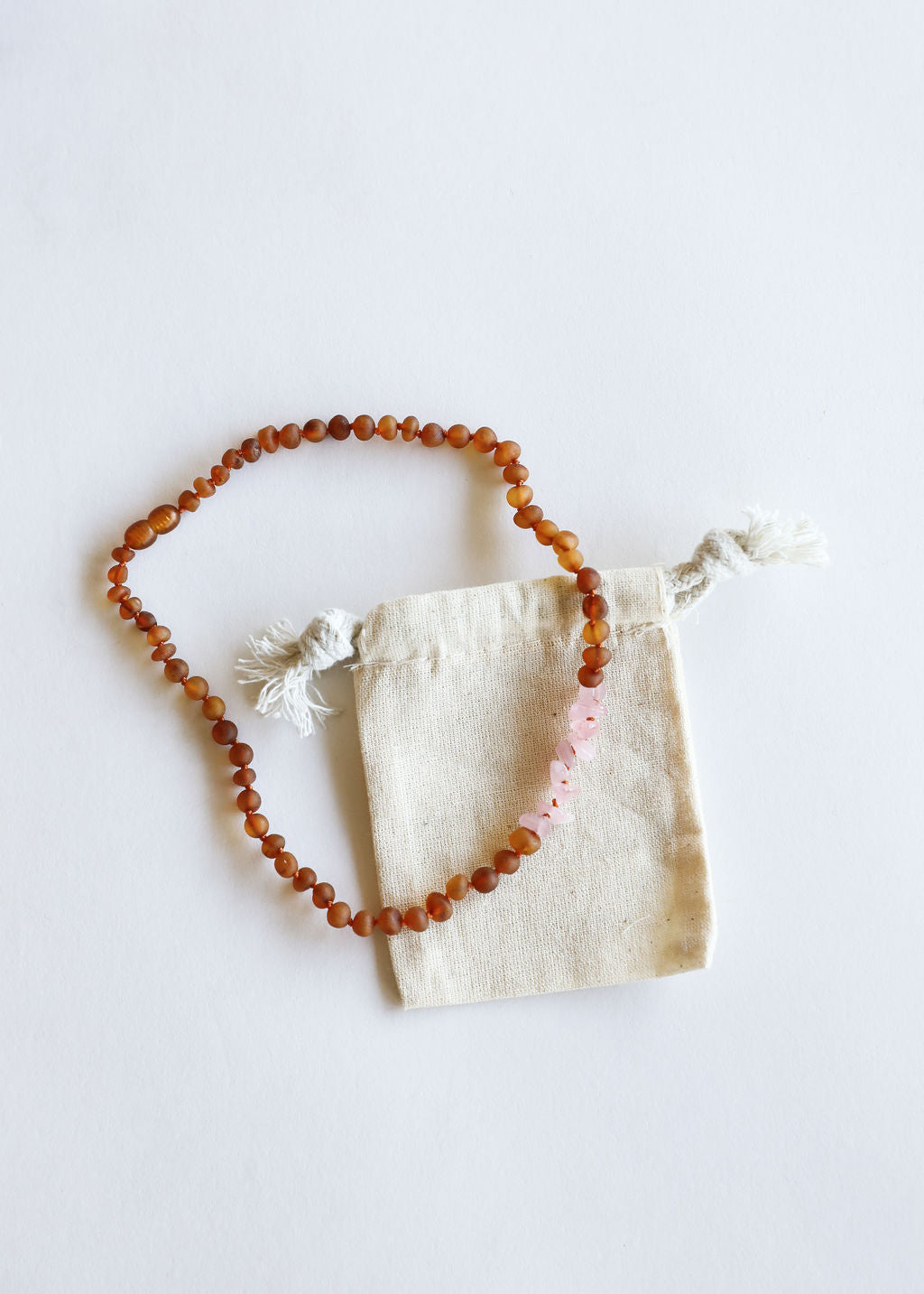 Raw amber bead necklace with pale pink stone accents and knotted ends