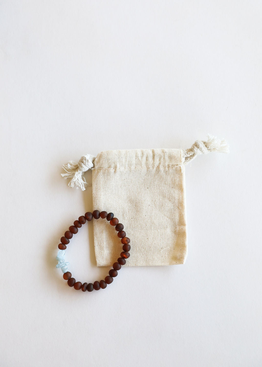 Adult bracelet with dark brown beads and raw light blue accent, with drawstring pouch