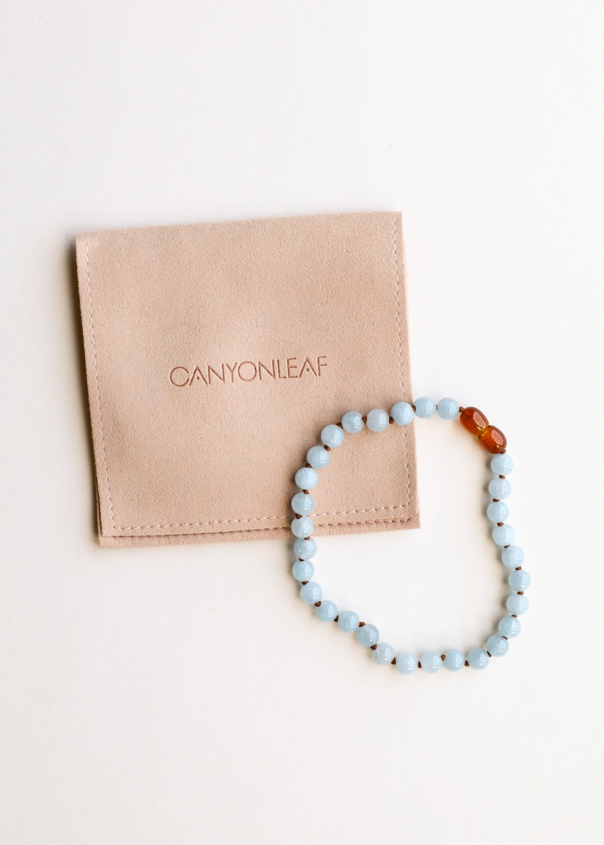 Aquamarine bead bracelet with amber accent beads, shown with storage pouch