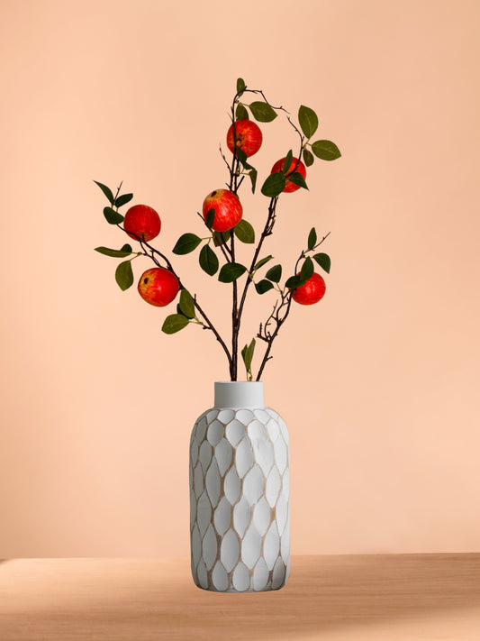 Artificial apple stems with red apples and green leaves in a textured ceramic vase