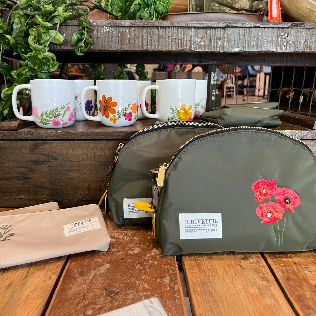 Olive nylon zip pouch with red floral embroidery, front label, gold chain and zipper pulls