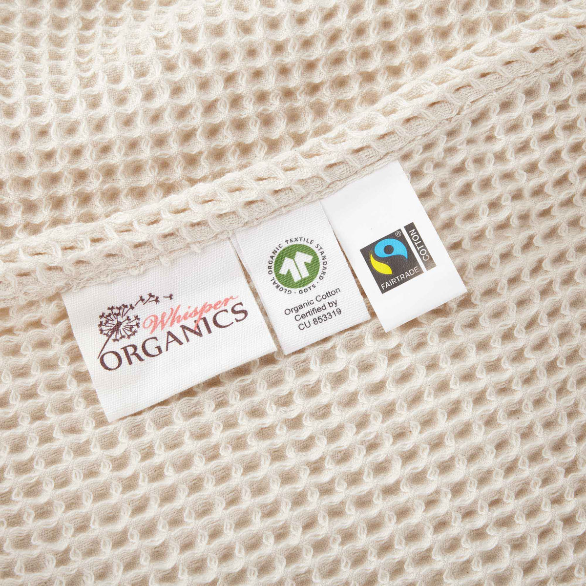 Natural waffle-knit blanket edge with fabric labels and stitched border.