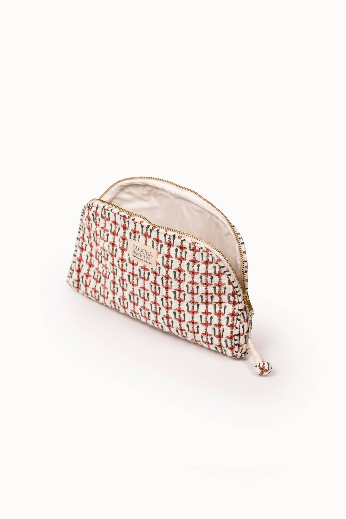 Quilted travel pouch with crimson block-print exterior and light beige interior.