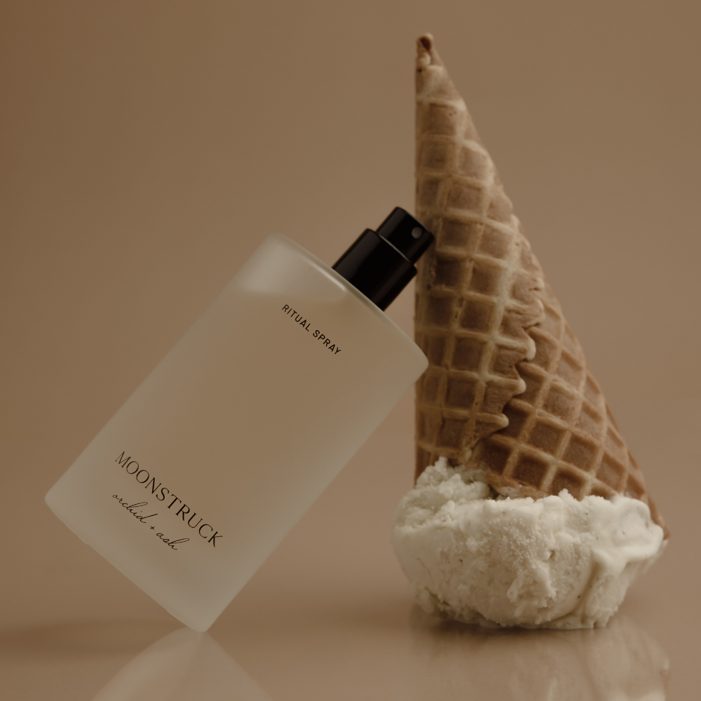 MOONSTRUCK ritual spray bottle with black pump beside waffle cone and white cream.