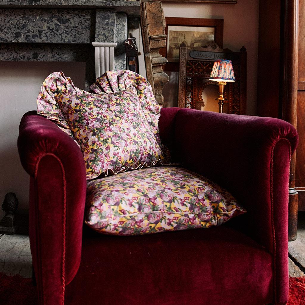 Floral ruffled pillow cover on a chair, yellow base with pink and green flowers