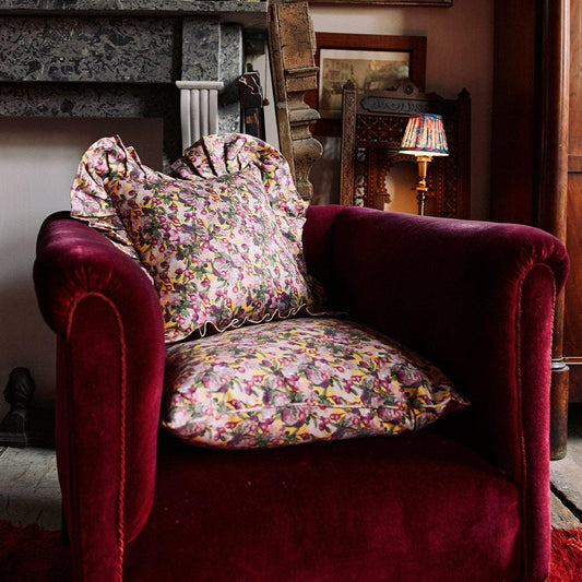 Floral ruffled pillow cover on a chair, yellow base with pink and green flowers