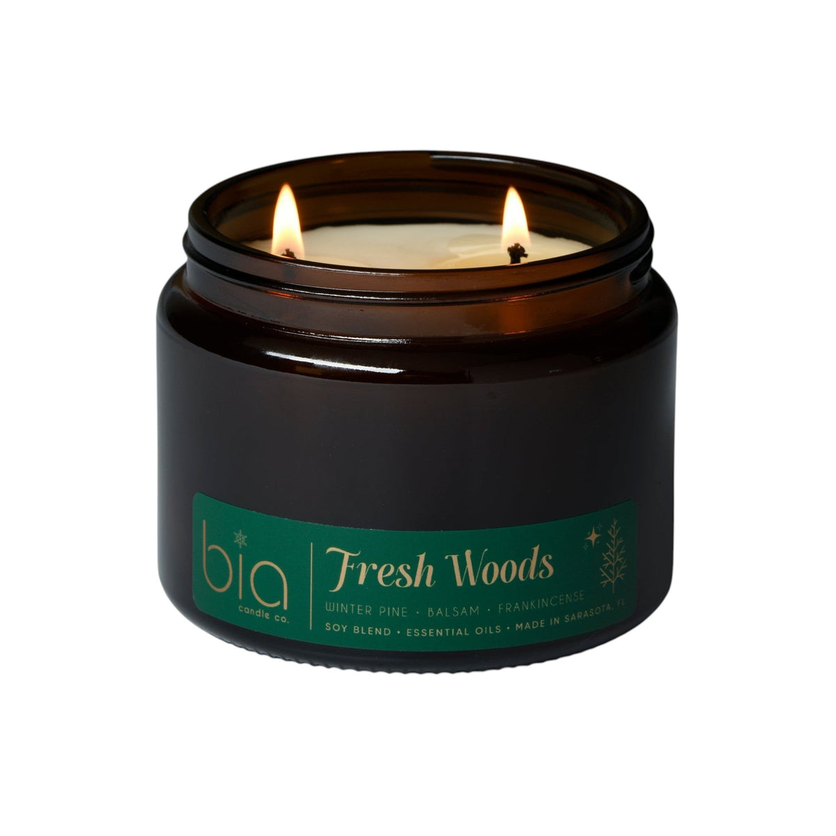 Black glass candle jar with lit wick and green label, Fresh Woods