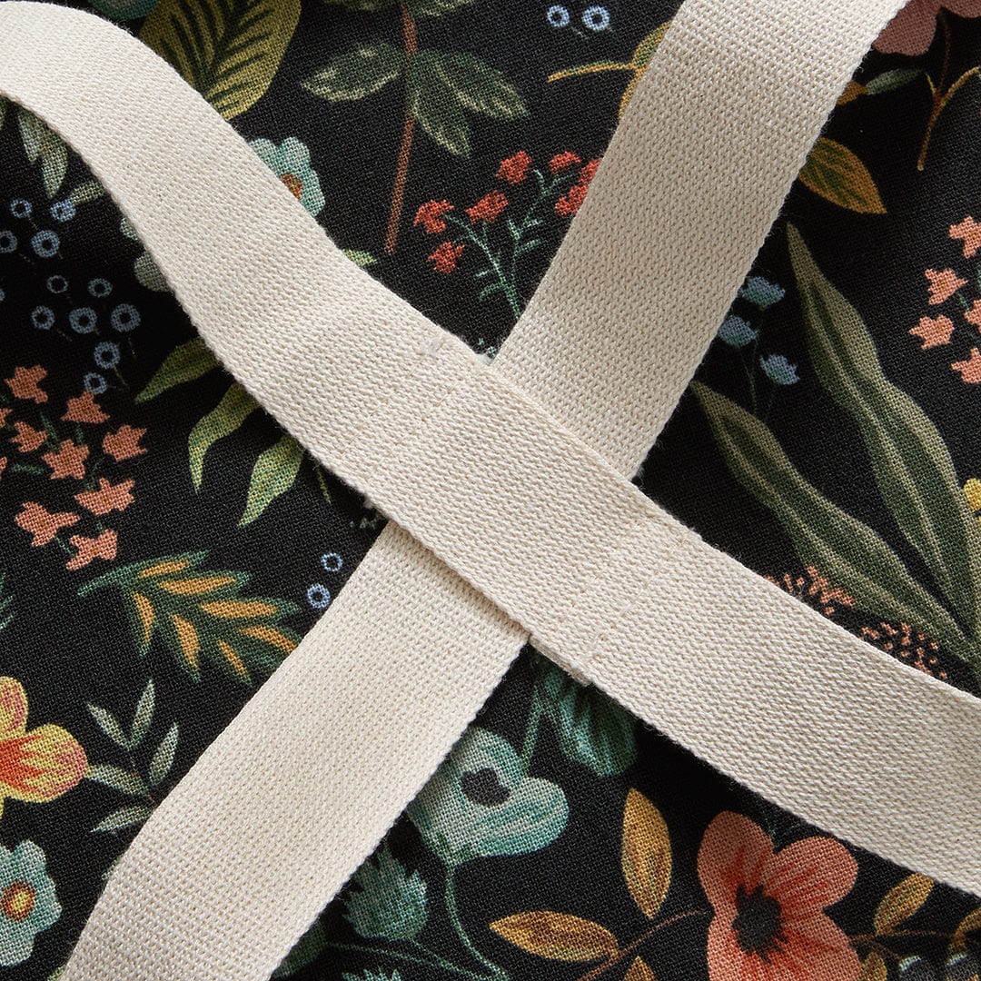 Beige crossback strap detail over black floral apron fabric