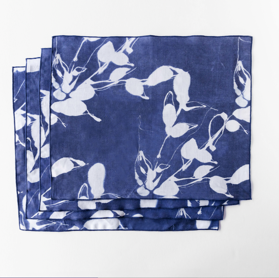 Overlapping stack of indigo placemats with white bird-and-flower motifs