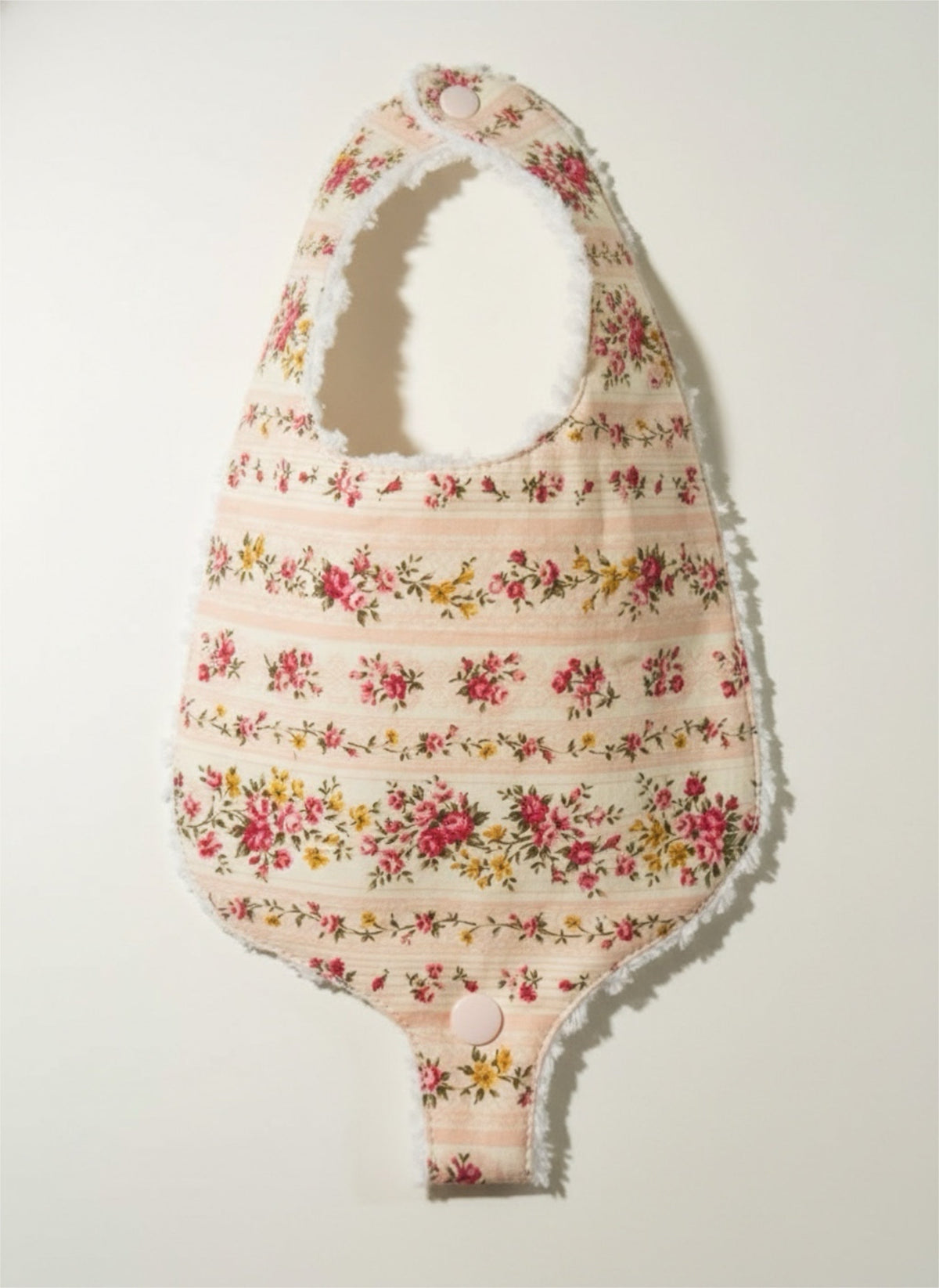 Floral pacifier bib with all-over meadowlark print and visible snap details at bottom.