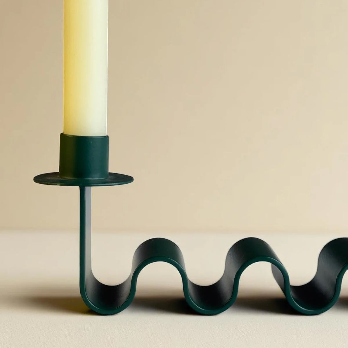 Forest green wavy base candle holder with one cup holding a cream taper candle