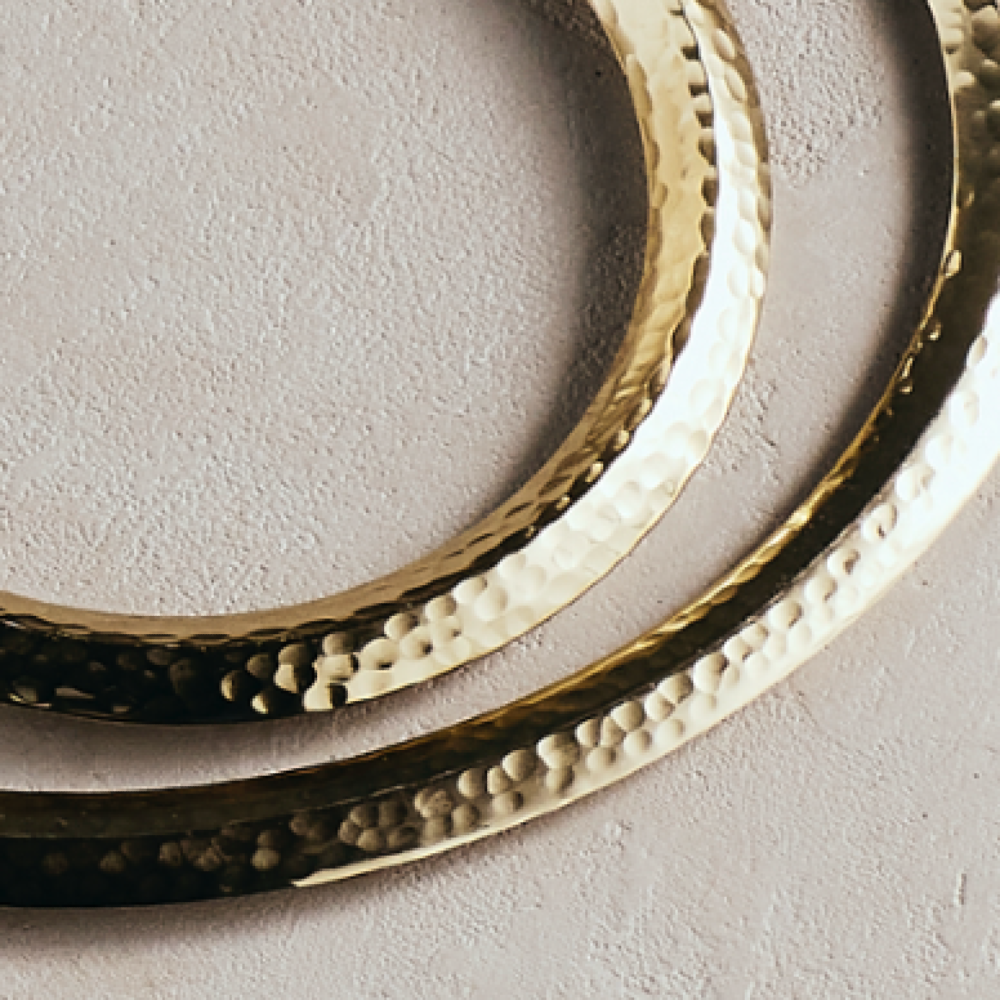 Close-up of nested hammered trivets with raised gold dots on dark metal rim.