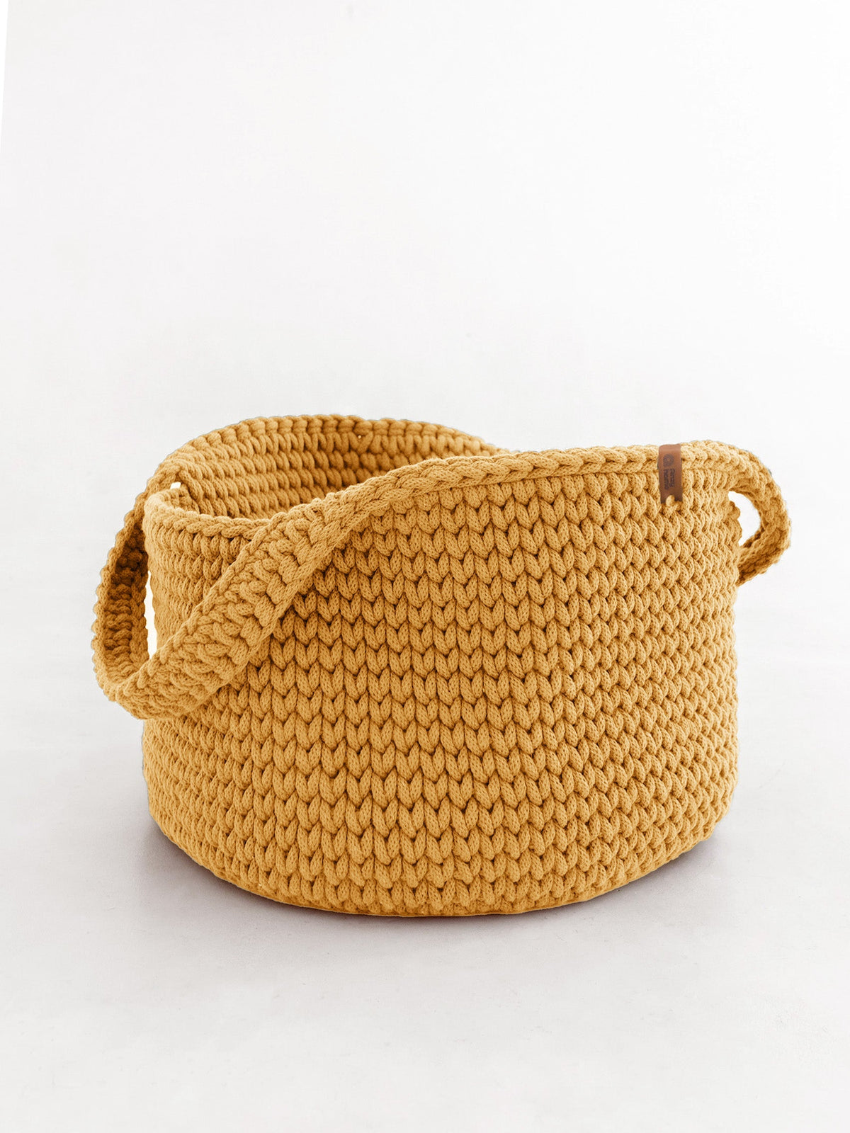 Round woven basket with handles, mustard-gold woven knit texture.