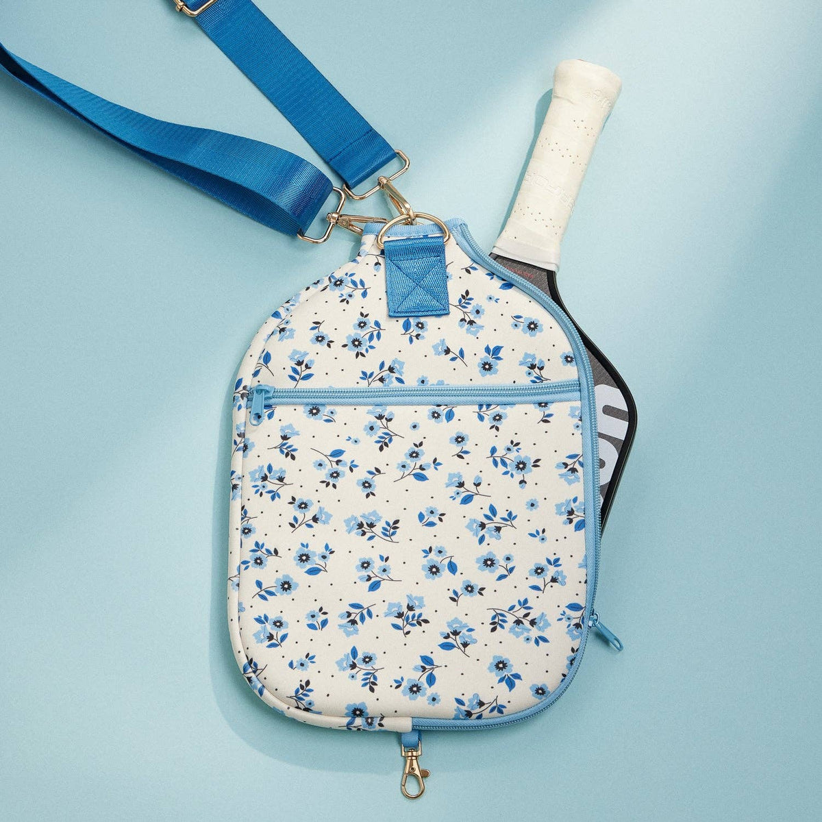 Blue floral paddle bag with front zip pocket, shoulder strap, and paddle handle visible