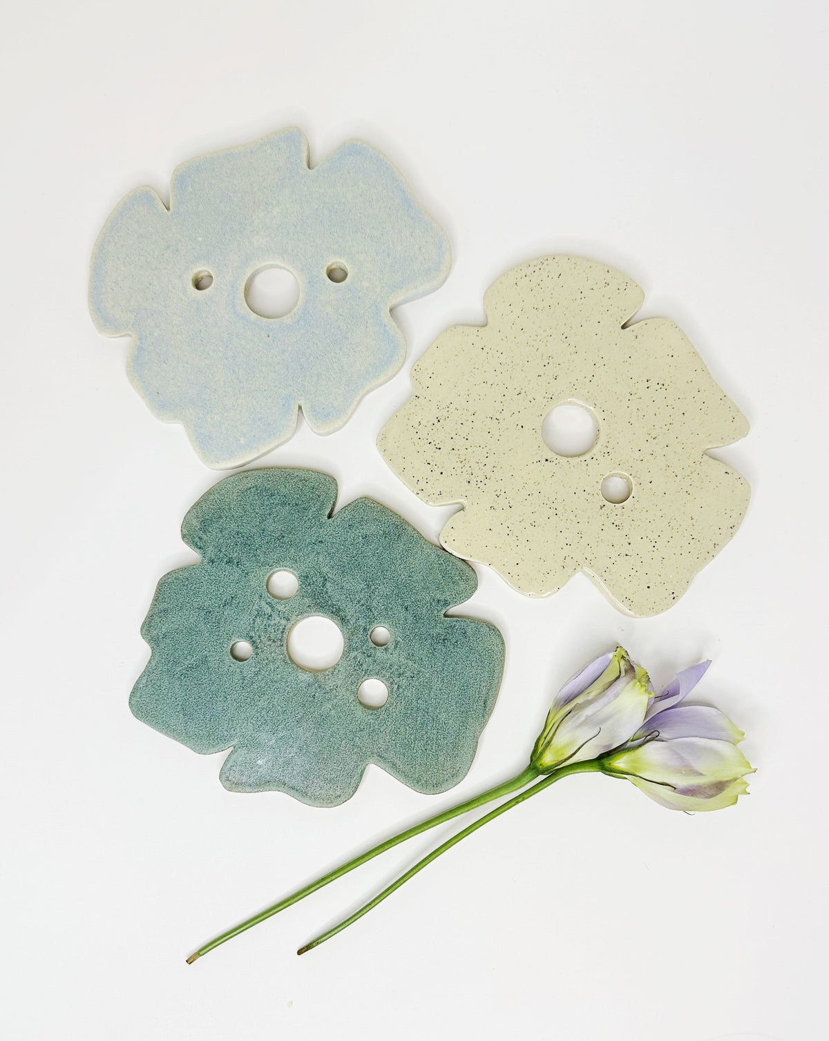 Three frog-shaped decor pieces in light blue, cream, and teal with round holes