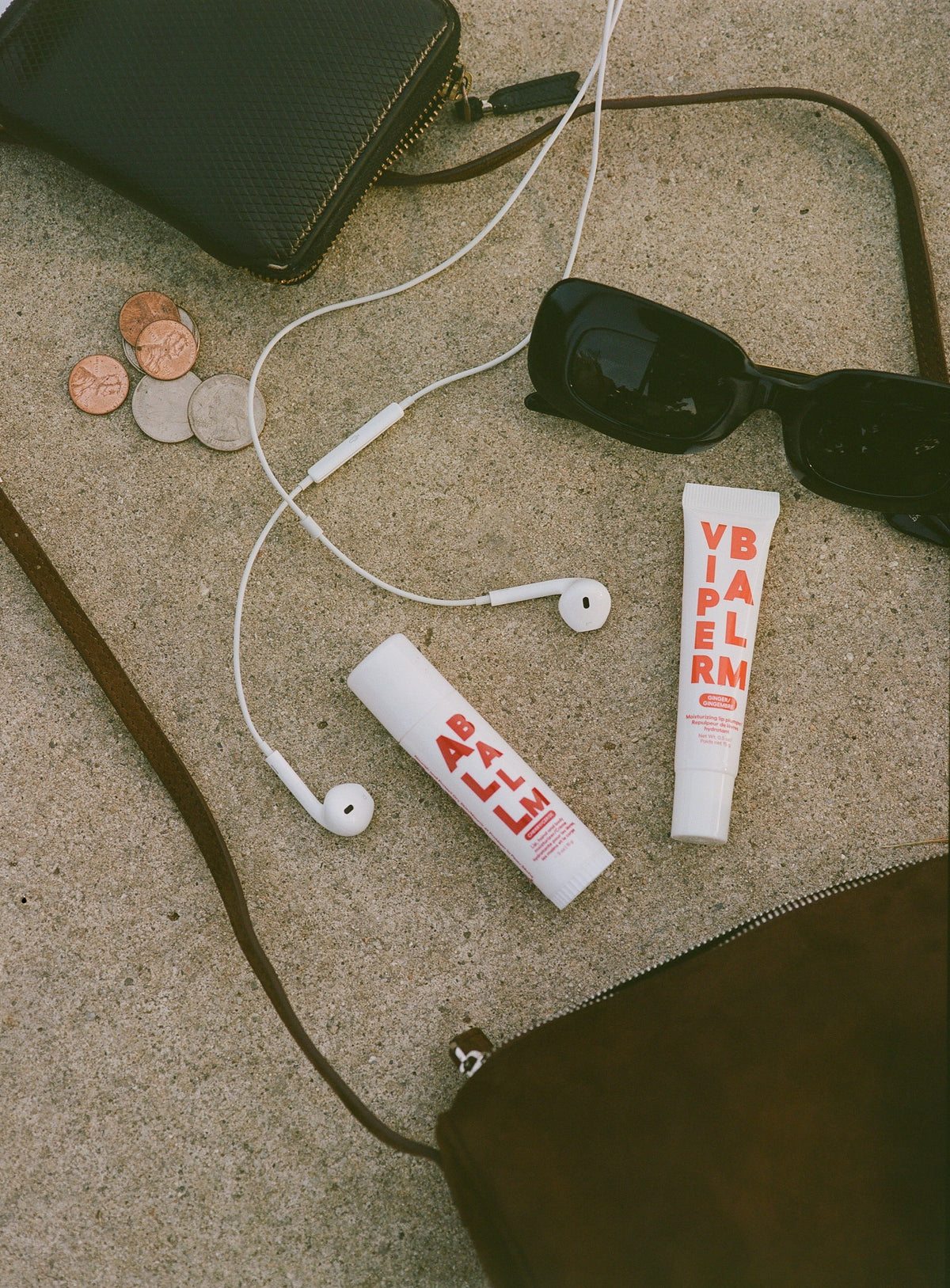 Balm stick tubes with white caps lying on a corded pouch set