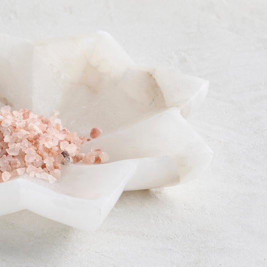 Close-up low alabaster bowl with pink crystal salt and ruffled edges