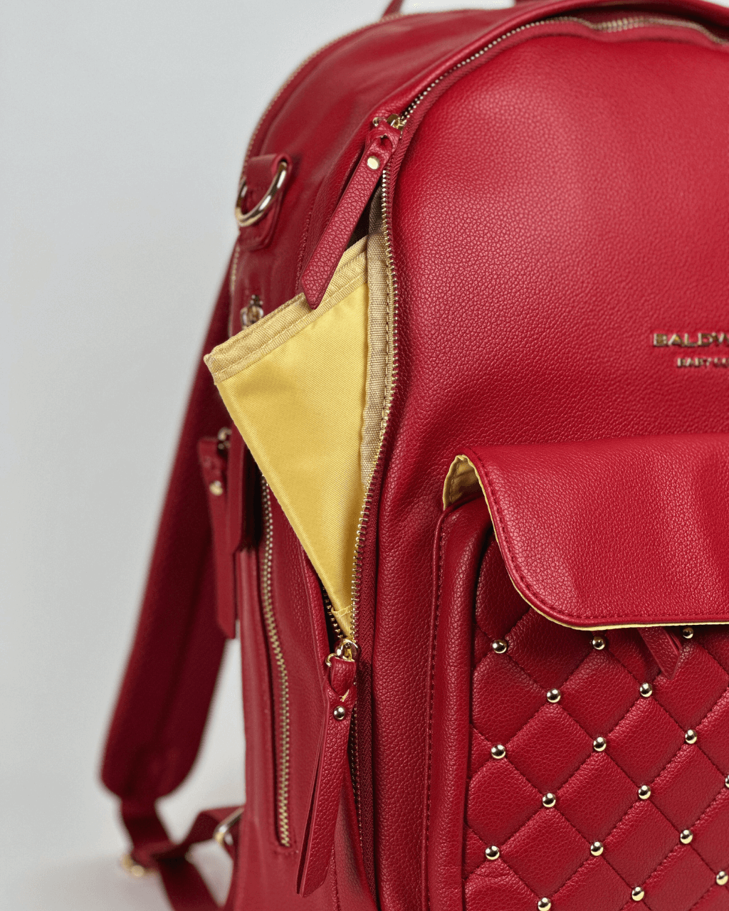 Close-up of the crimson diaper bag's side zipper and gold lining.