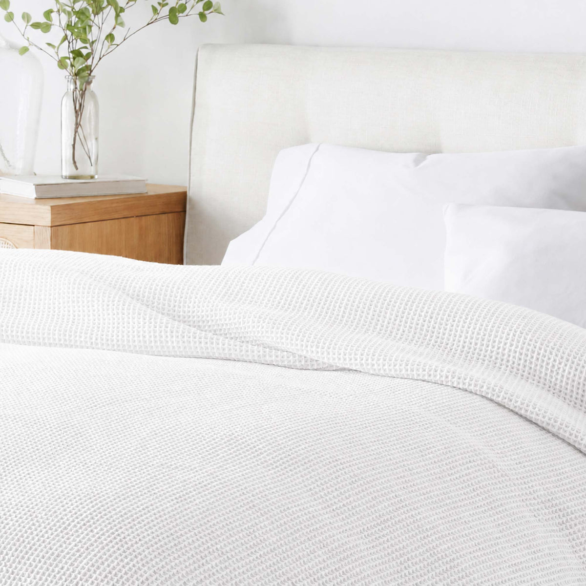 White waffle-knit blanket folded on bed, fine textured grid pattern.
