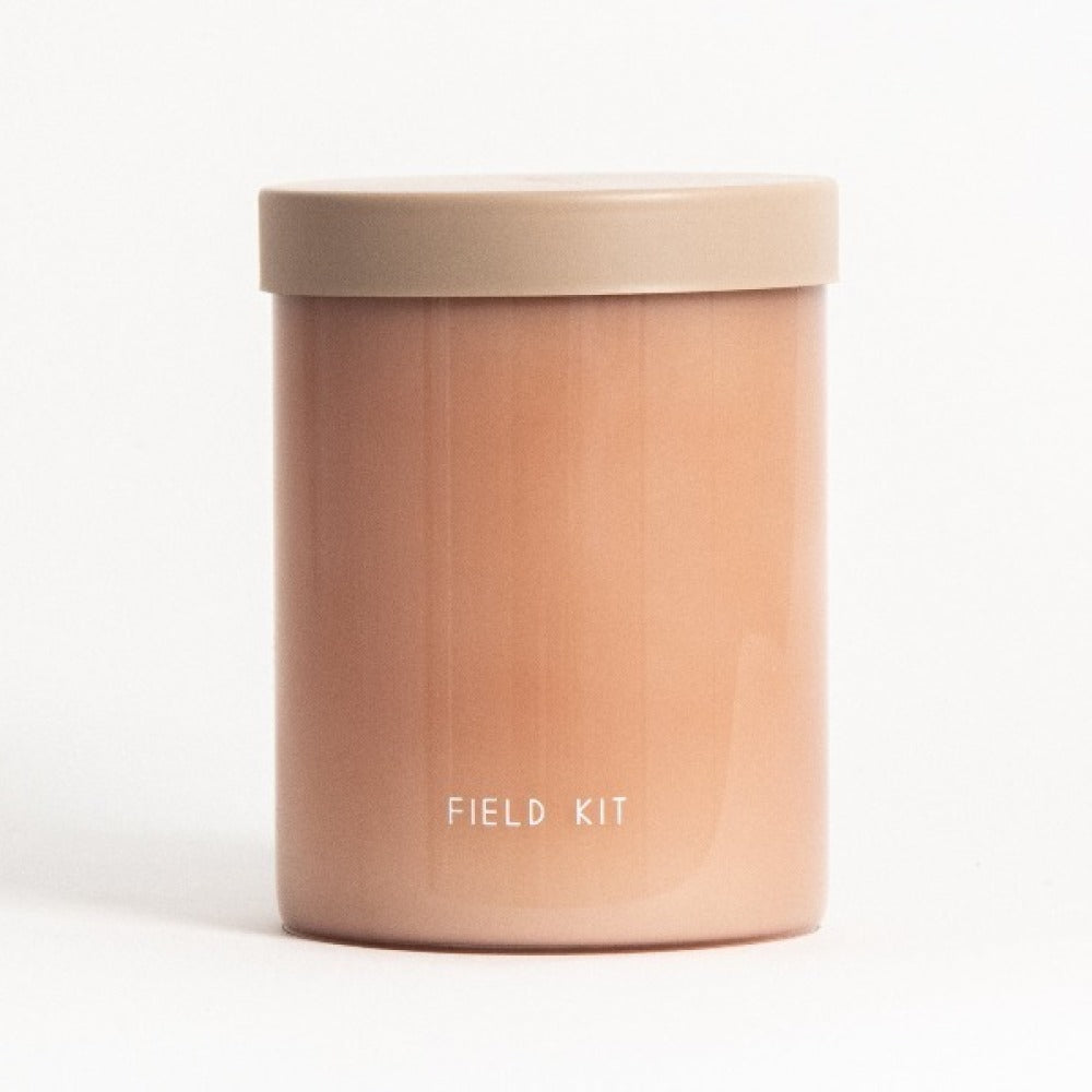 Beige-lidded candle jar with "Field Kit" on the front, copper-toned container.