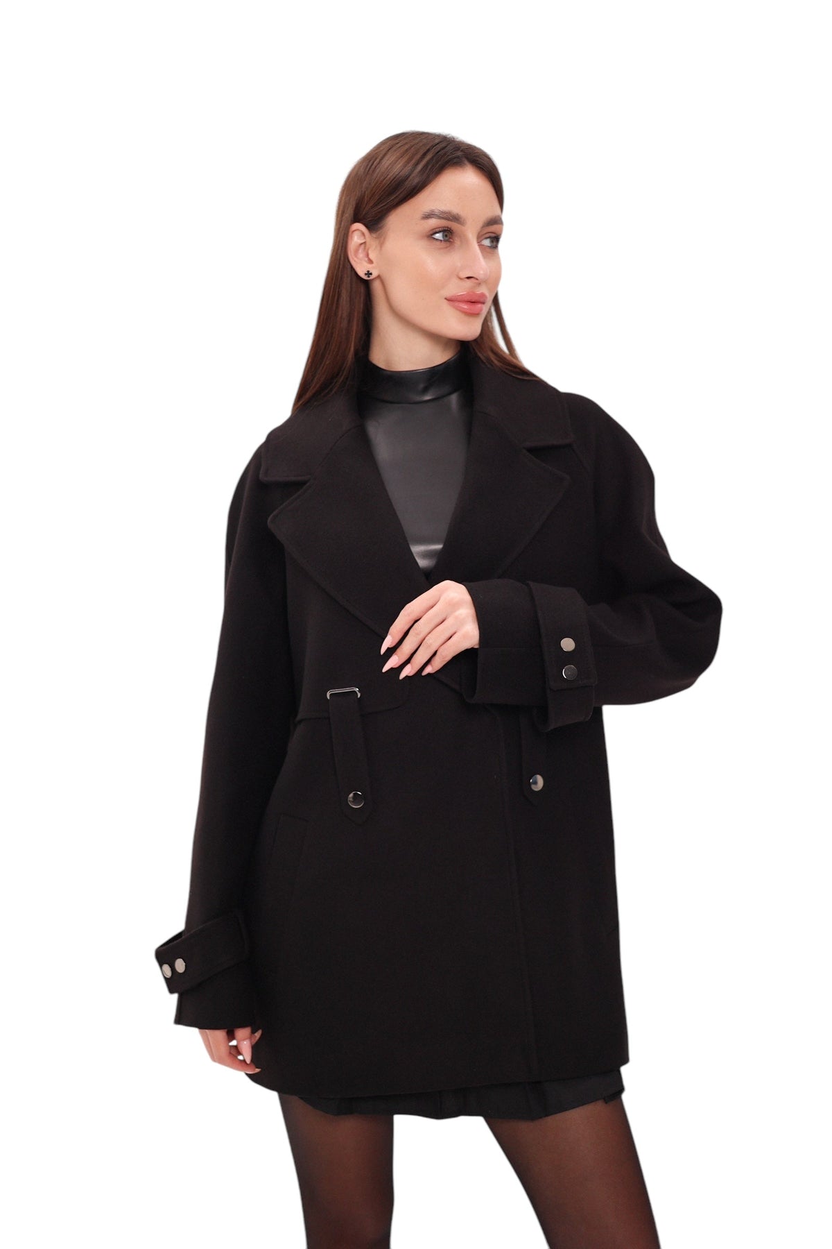Black midi coat worn closed with wide lapels, belt loops, and cuff buttons