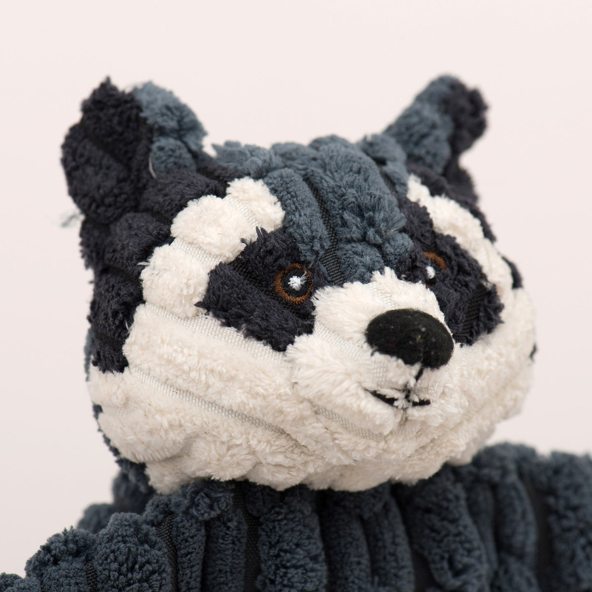 Close-up of gray and white plush wolf toy face with embroidered eyes