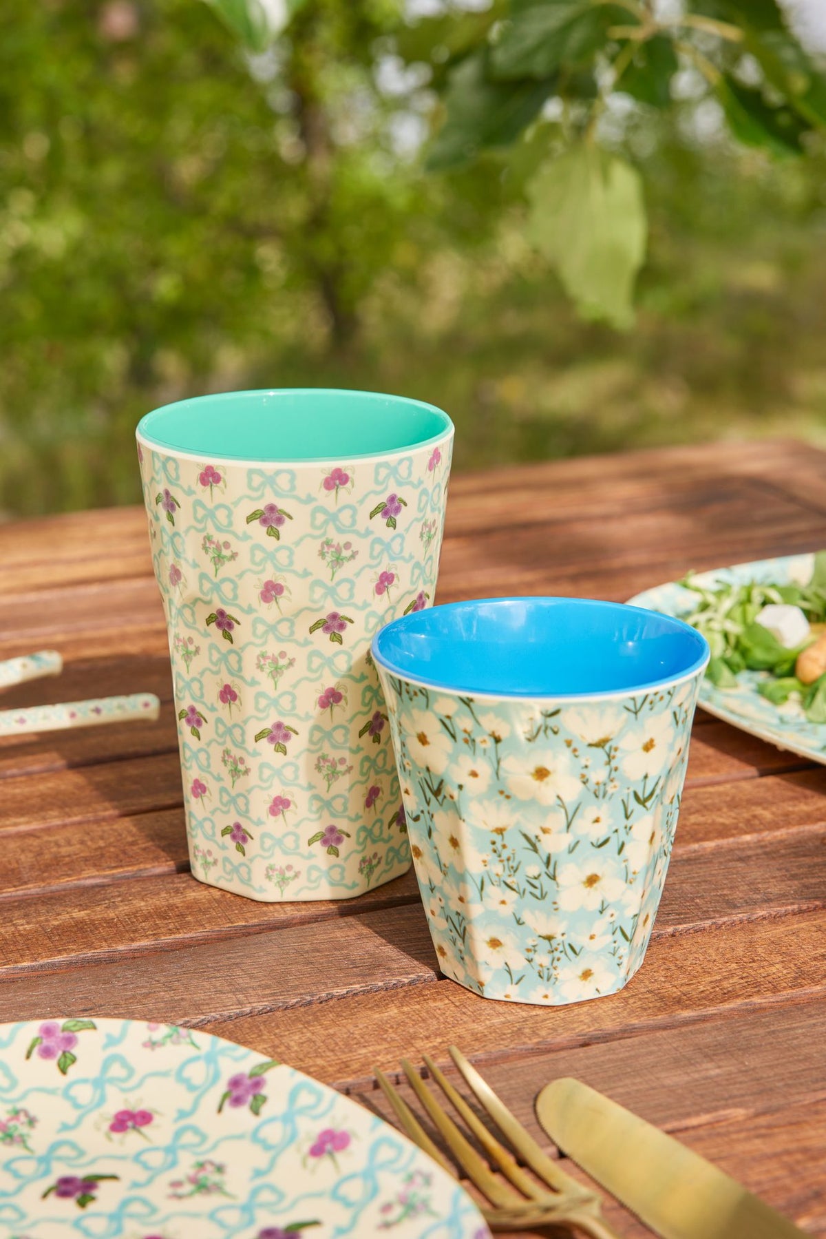 Two melamine cups with floral prints and blue interiors on a table