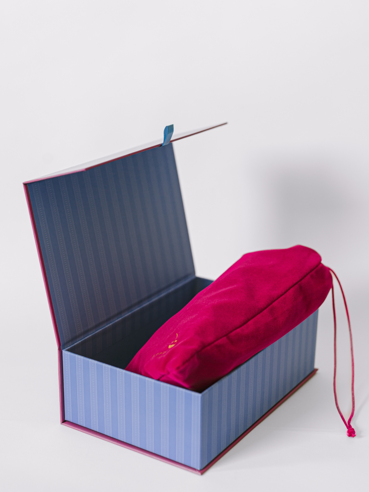 Jigsaw puzzle box open with striped interior and magenta sleeve holding puzzle pieces