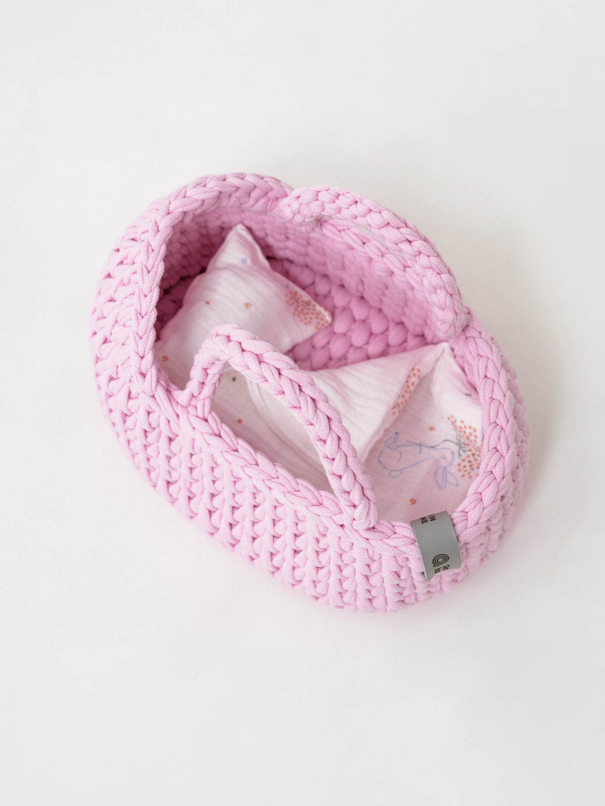 Pink knit mini doll moses basket with patterned inner pad and folded fabric liner