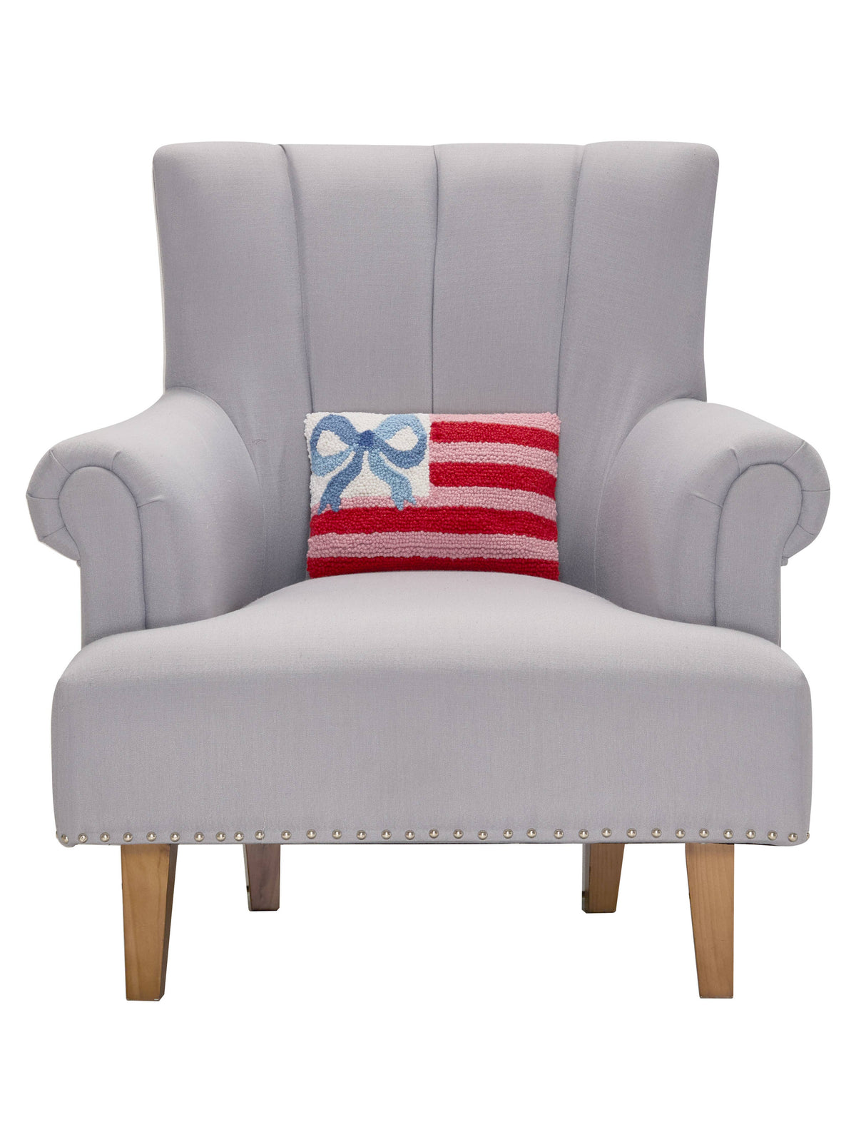 Decorative pillow with blue bow and red-and-white striped insert on gray armchair
