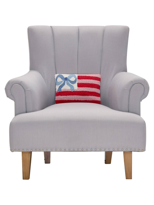 Decorative pillow with blue bow and red-and-white striped insert on gray armchair
