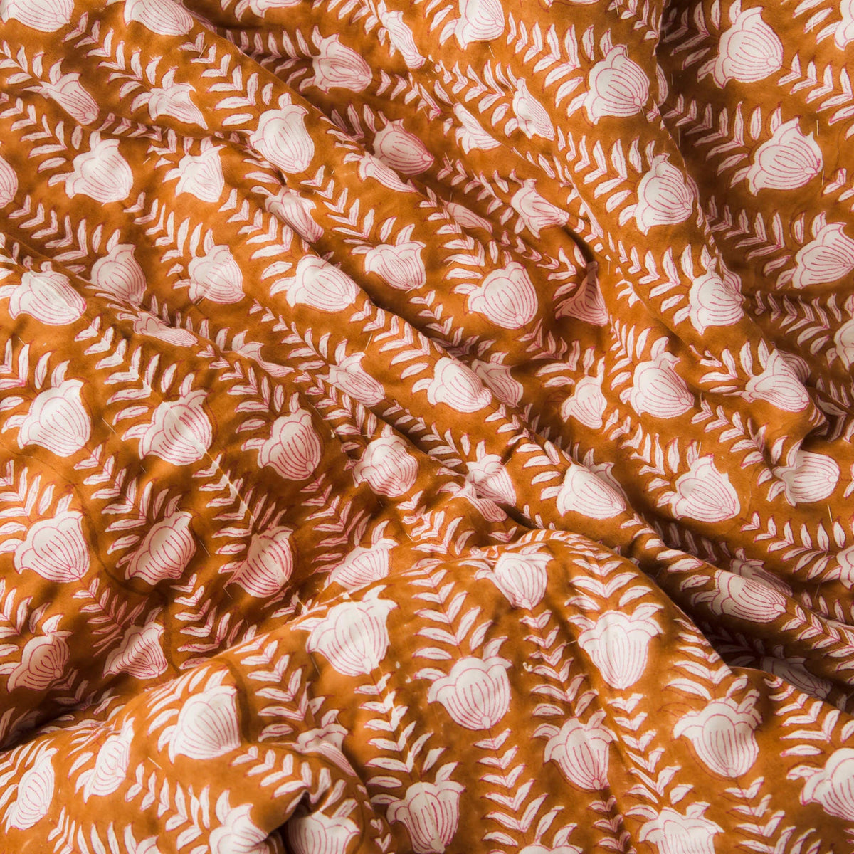 Close-up of brown cotton throw fabric with repeating white leaf-like and zigzag pattern