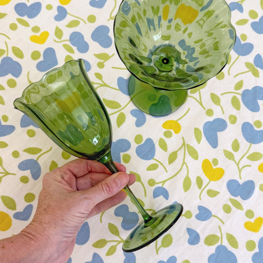Hand holding a green handblown water glass with flared rim and stem base