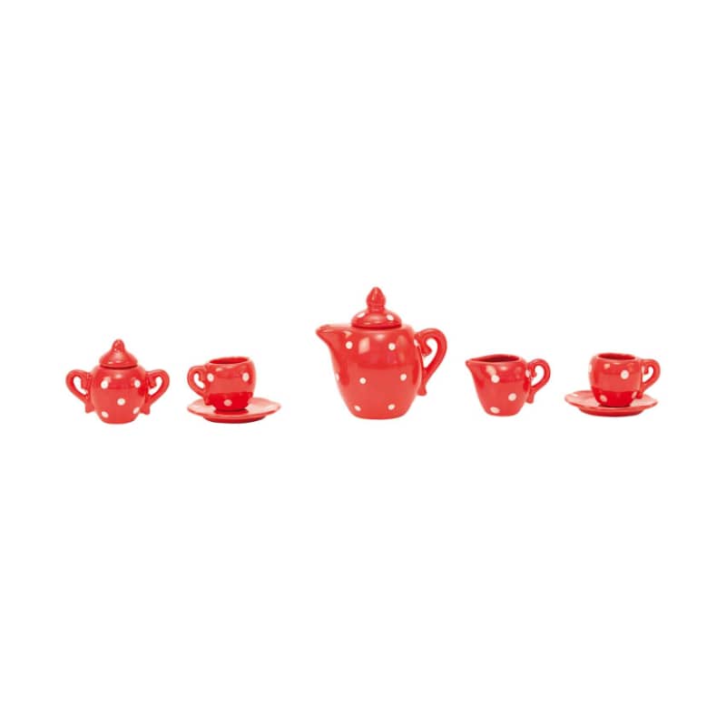 Red polka dot ceramic tea set arranged in a row with teapot, cups, and saucers