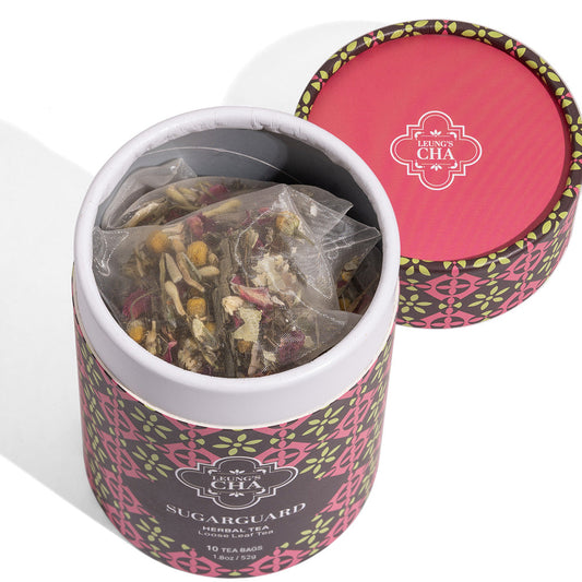 Herbal tea tin with open top and visible tea leaves inside, pink patterned lid