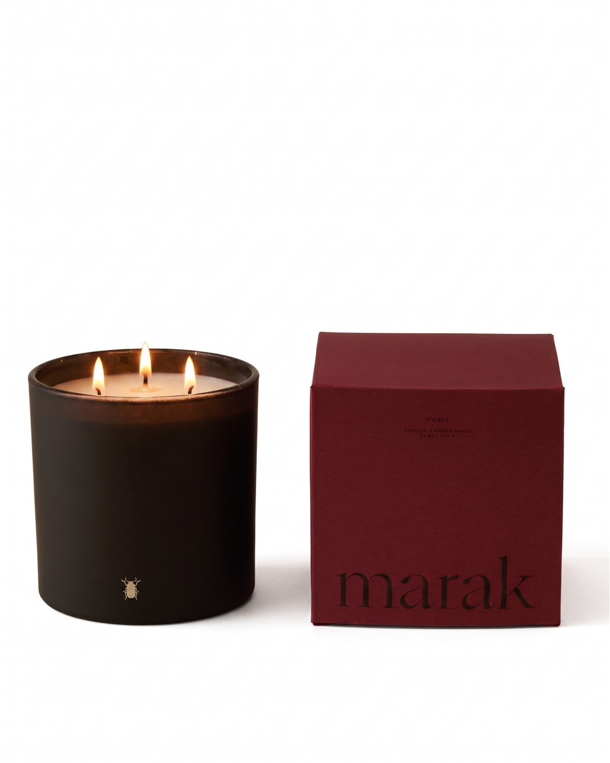 Black marak jar candle with flame beside maroon Vanilla & Amber Wood gift box