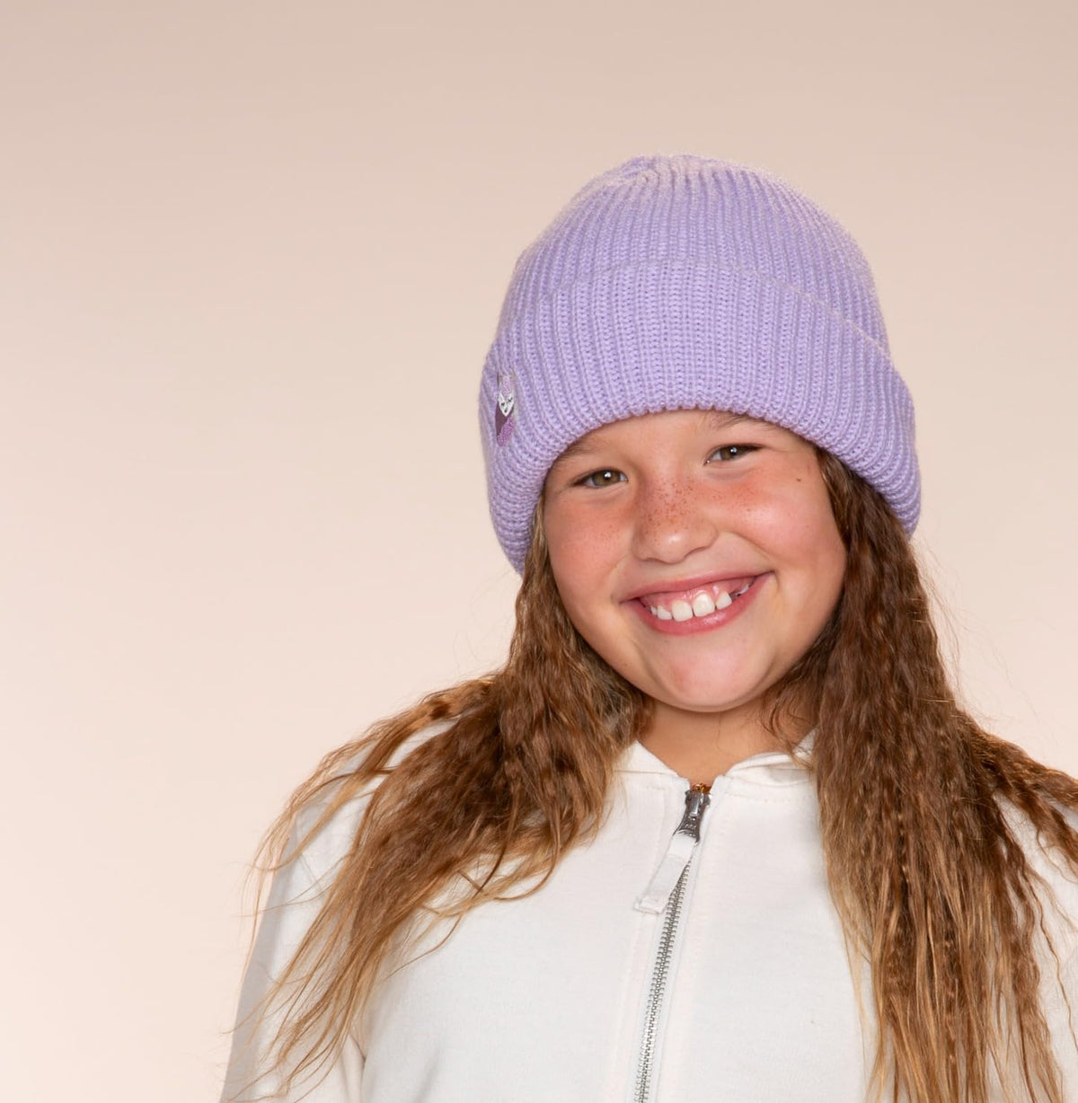 Lavender knitted beanie with a small fox patch, worn on a child